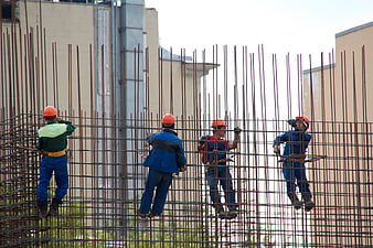 Construction workers reinforcing steel rebar cage on building site