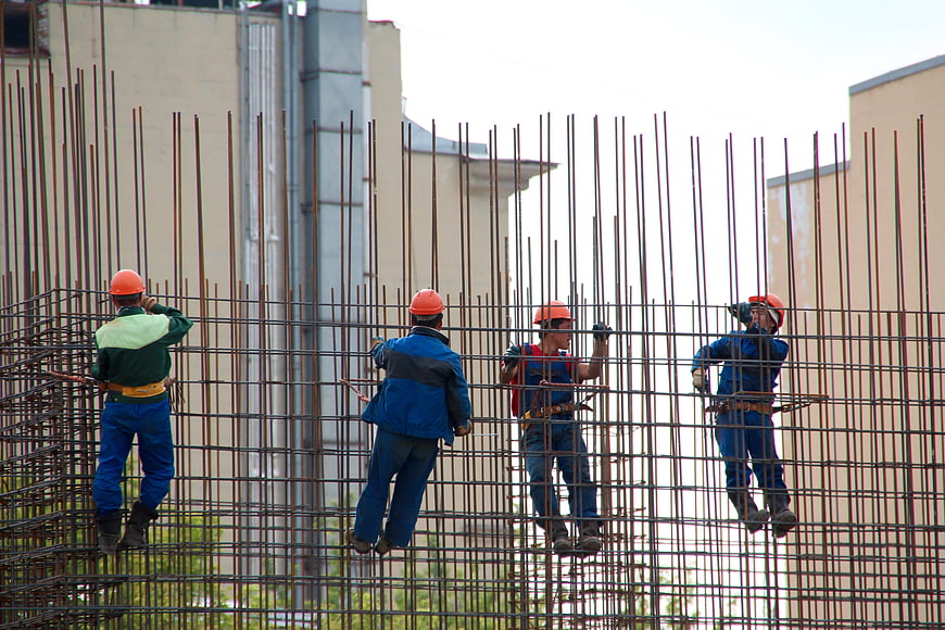 Construction workers reinforcing steel rebar cage on building site
