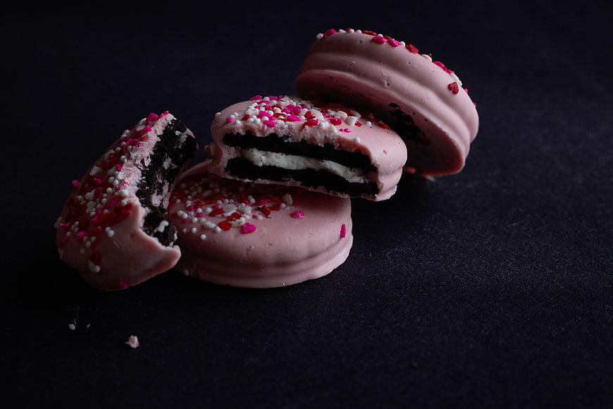 Pink Chocolate Covered Cookies with Sprinkles on Dark Background