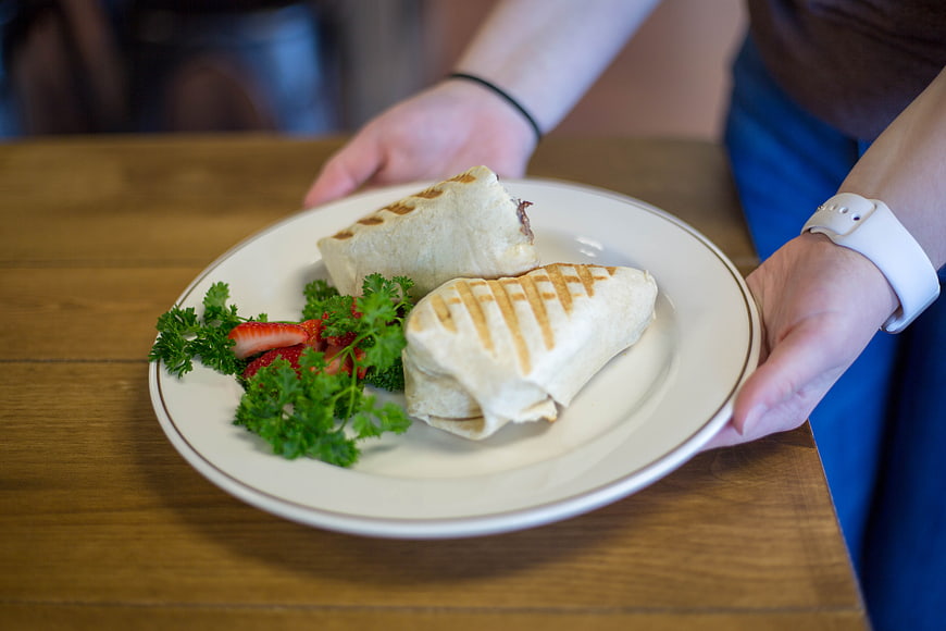 Waitress Serving Grilled Wraps on White Plate