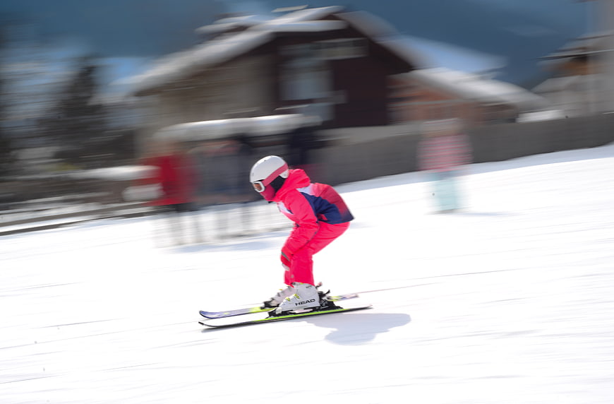 Child Skiing Downhill in Pink Snowsuit