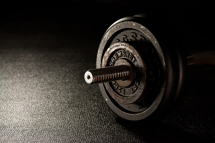 Close-up of vintage iron dumbbell on dark textured surface