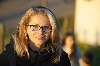 Portrait of a smiling blonde woman wearing glasses in golden hour light