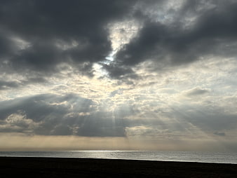 Dramatic Sun Rays Breaking Through Storm Clouds Over Ocean