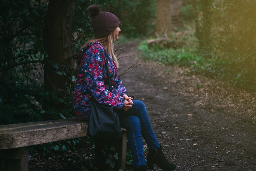 Woman in Beanie Sitting on Park Bench in Forest