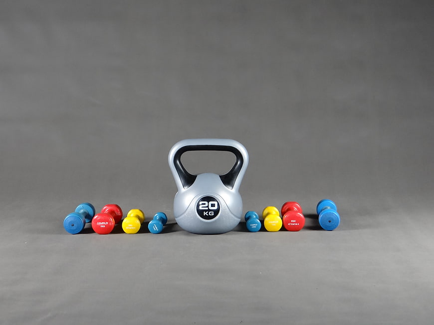 Silver Kettlebell and Colorful Dumbbells on Gray Background