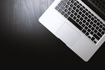 Silver laptop keyboard and trackpad on dark wooden desk