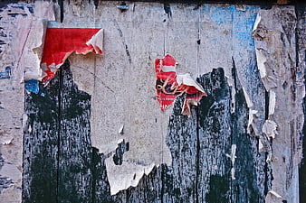 Weathered wooden fence with peeling paint and torn red paper