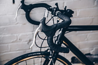 Close-up of black bicycle handlebars against white brick wall