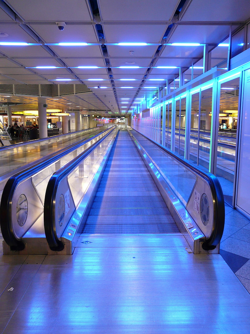 Futuristic moving walkway in modern transit hub with blue neon lighting