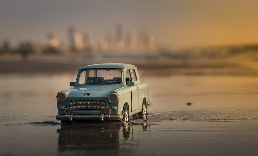Vintage Miniature Car on Wet Sand at Sunset