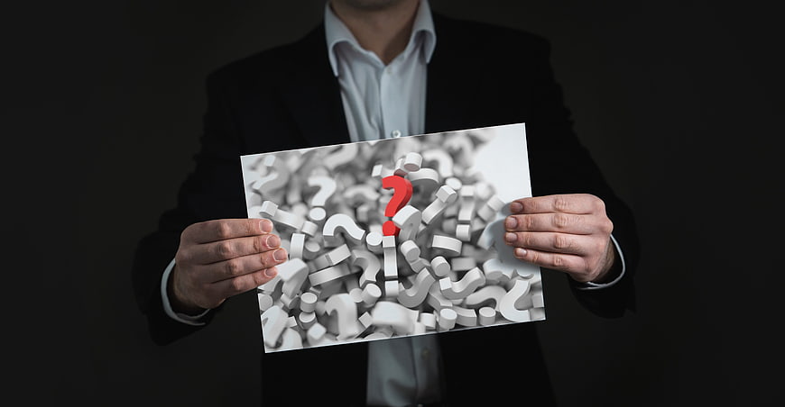 Businessman holding conceptual image of question marks
