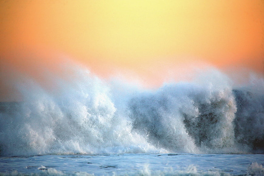 Dramatic Ocean Wave Spray Against Vibrant Sunset Sky