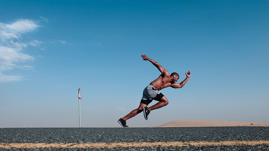 Athletic man sprinting on desert road