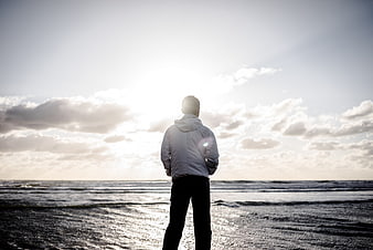Man standing on beach looking at ocean sunset