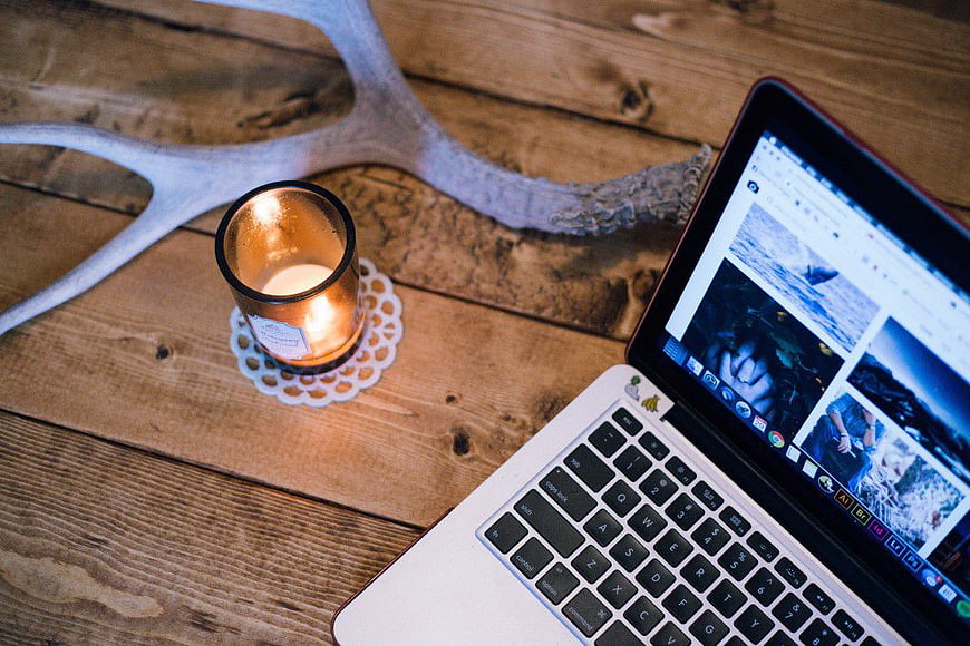Cozy Workspace with Laptop, Candle, and Antler on Wood