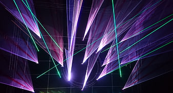 Vibrant purple and green laser light show beams at night