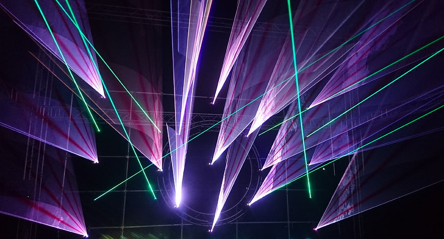 Vibrant purple and green laser light show beams at night