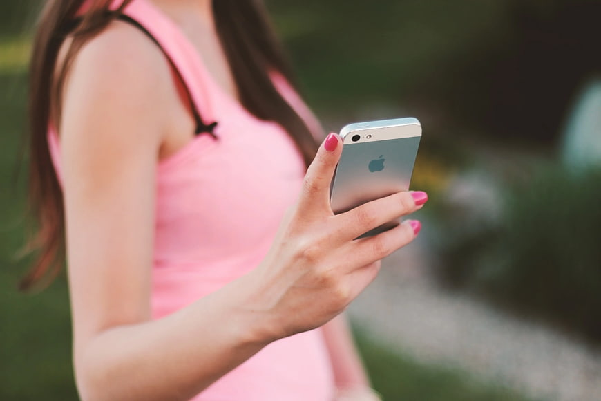 Woman in Pink Top Holding Smartphone Outdoors