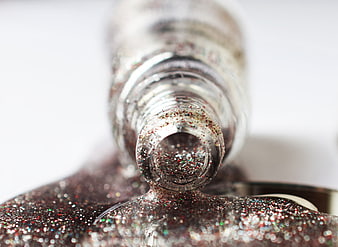 Macro shot of silver glitter nail polish bottle and texture