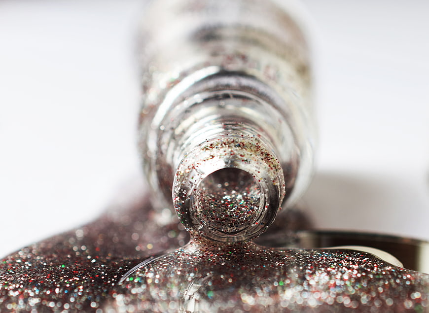 Macro shot of silver glitter nail polish bottle and texture