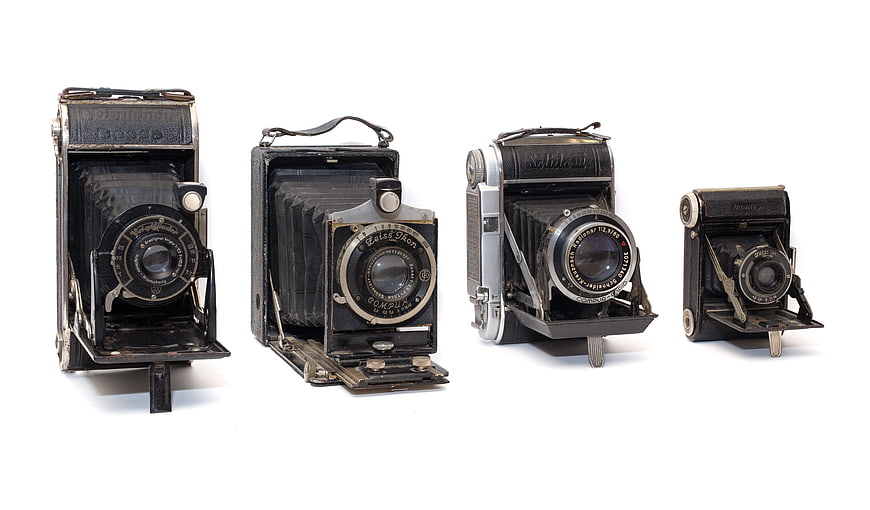 Collection of vintage German folding cameras on white background