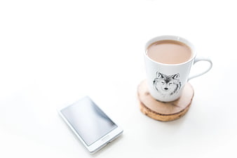 Minimalist coffee cup and smartphone on white background