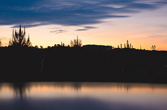 Serene Lake Sunset with Silhouetted Trees and Reflection