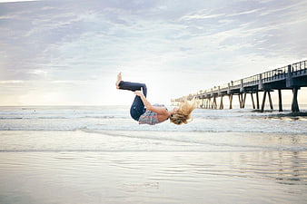 Woman Jumping Upside Down on Beach at Sunset