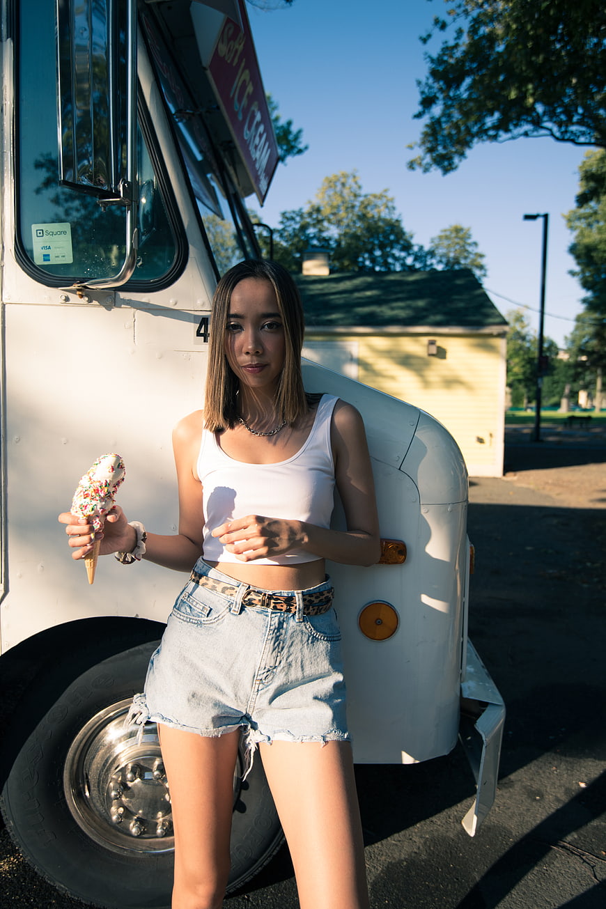 Young woman eating ice cream cone by vintage truck