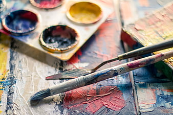 Close-up of artist palette, paintbrush, and palette knife on canvas