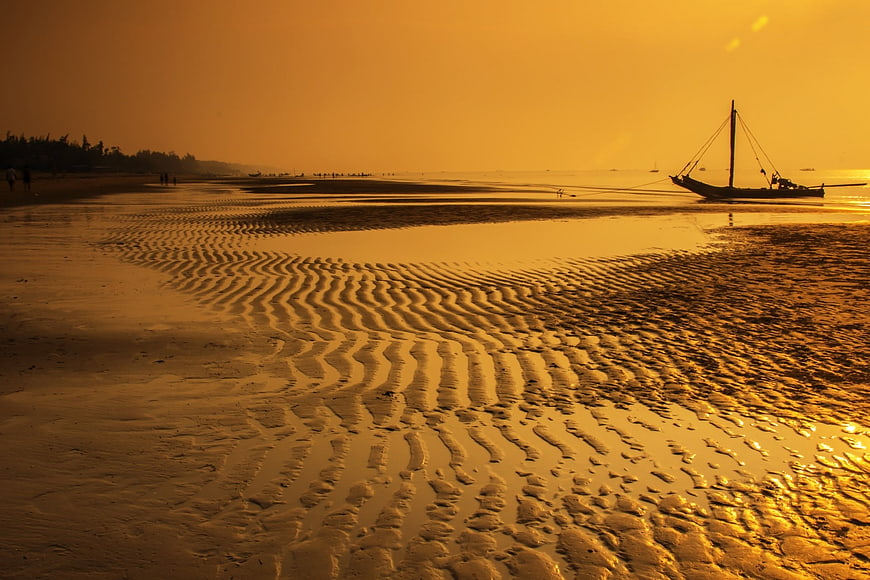 Silhouette of Fishing Boat on Golden Sandy Beach at Sunset