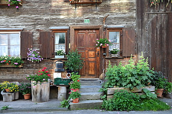 Rustic wooden house facade with colorful flower boxes and garden