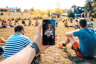 Hand holding smartphone with motivational quote in park