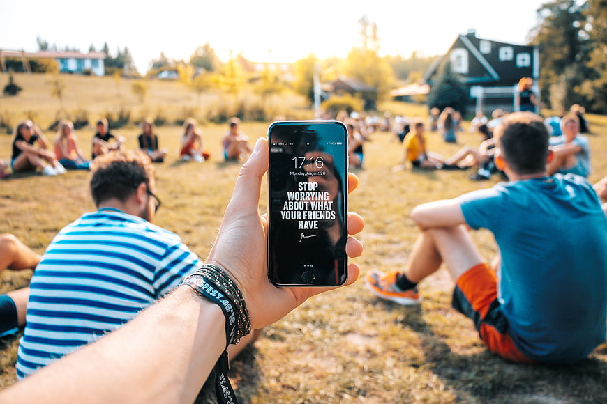 Hand holding smartphone with motivational quote in park