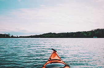 Orange Kayak on Calm Lake with Forest Shoreline