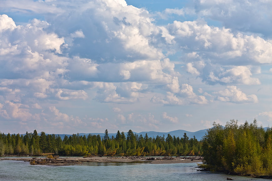 Wide river landscape with autumn aspen trees and dramatic clouds