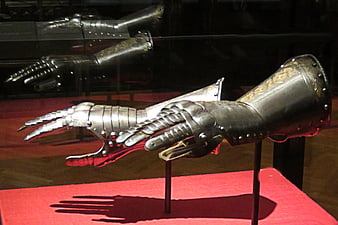 Medieval steel gauntlets on display with red background