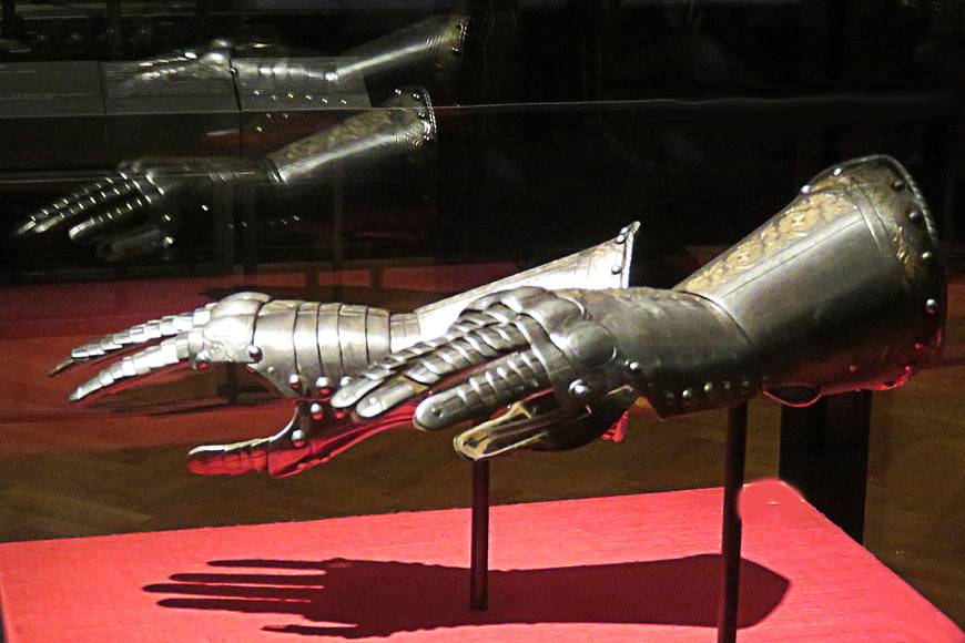 Medieval steel gauntlets on display with red background
