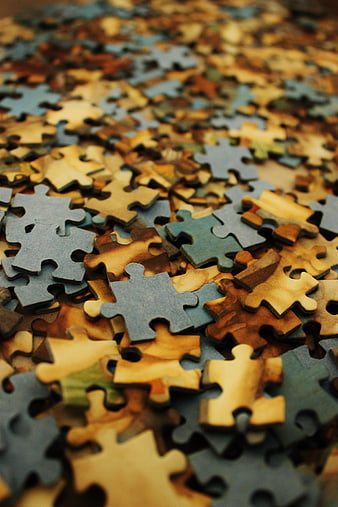 Close-up of scattered wooden jigsaw puzzle pieces in warm tones