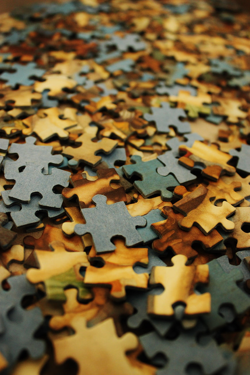 Close-up of scattered wooden jigsaw puzzle pieces in warm tones