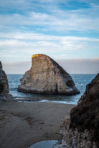 Sunlit Sea Stack Rock Formation on Sandy Beach
