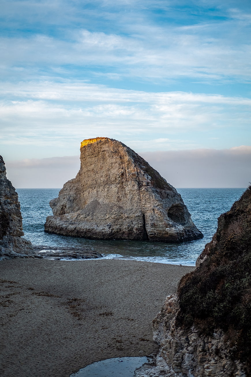 Sunlit Sea Stack Rock Formation on Sandy Beach