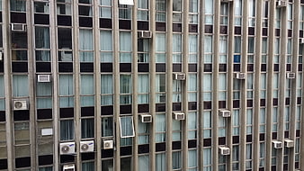 Vertical facade of modern apartment building with windows and air conditioners