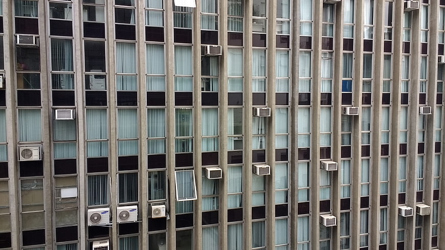 Vertical facade of modern apartment building with windows and air conditioners