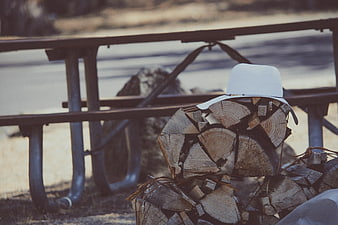 White Hat on Pile of Firewood Near Picnic Table