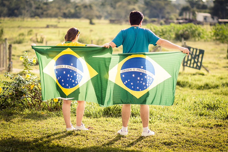 Couple holding Brazilian flag in green field