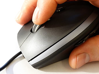 Close-up of hand using black computer mouse on white surface
