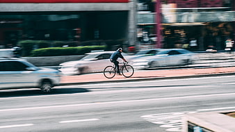 Cyclist riding bike on city street with motion blur traffic