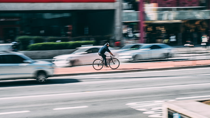 Cyclist riding bike on city street with motion blur traffic